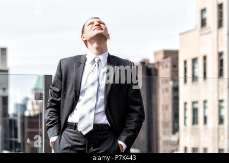 Young businessman standing in business suit à la recherche jusqu'à sky à New York Ville paysage urbain dans le centre de Manhattan skyline après entrevue pause à skyscra Banque D'Images