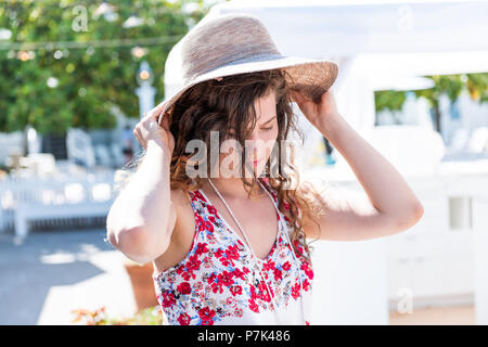 Jeune femme libre de shopping pour la paille beach hat en essayant sur marché plein air shop store en Europe, Grèce, Italie, ville, village en Méditerranée Banque D'Images