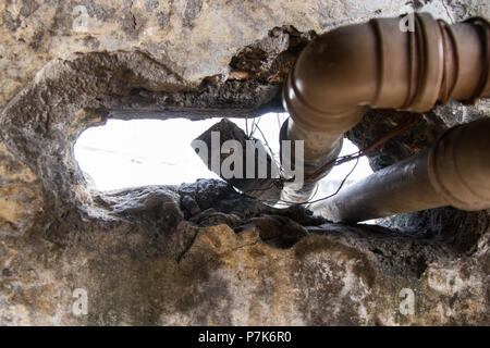 Énorme trou dans un mur fissuré est utilisé de passage de tuyaux d'eau dans un bâtiment utilisé comme slum condamné par le logement social mouvement. San Paolo. Le Brésil. Pas de p Banque D'Images