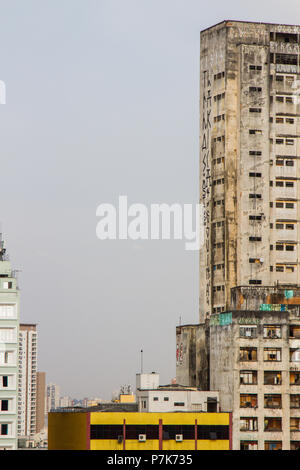 Condamné abandonné énormes bâtiments utilisés comme logements sociaux bidonville par le mouvement sur l'arrière-plan d'un ancien bâtiment résidentiel jaune. San Paolo. Le Brésil. Banque D'Images