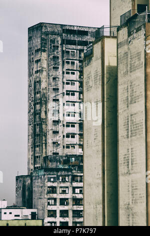 Condamné abandonné énormes bâtiments utilisés comme logements sociaux bidonville par le mouvement sur l'arrière-plan d'un ancien bâtiment résidentiel jaune. San Paolo. Le Brésil. Banque D'Images