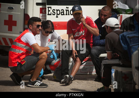 Malaga, Espagne. 7 juillet 2018. Un migrant, qui a été sauvé d'un canot à la mer Méditerranée, se trouve avec les membres de la Croix Rouge Espagnole après son arrivée au Port de Malaga. Les membres de la sécurité maritime espagnol a secouru 24 migrants à bord d'un canot près de la côte de Malaga et porté sur le port de Malaga, où ils étaient assistés par la Croix Rouge Espagnole. Credit : SOPA/Alamy Images Limited Live News Banque D'Images