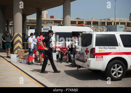 Malaga, Espagne. 7 juillet, 2018. Les migrants, qui ont été sauvés d'un canot à la mer Méditerranée, reste comme un agent de police promenades après leur arrivée au Port de Malaga. Les membres de la sécurité maritime espagnol a secouru 24 migrants à bord d'un canot près de la côte de Malaga et porté sur le port de Malaga, où ils étaient assistés par la Croix Rouge Espagnole. Credit : Jésus Merida/SOPA Images/ZUMA/Alamy Fil Live News Banque D'Images