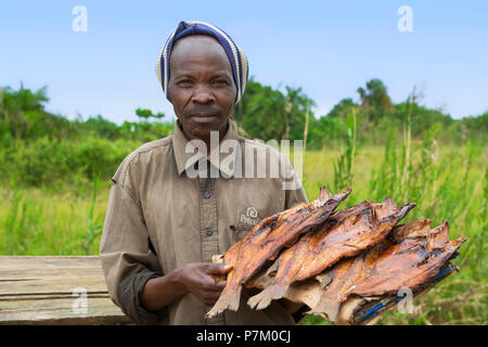 Tilapia fumé, Ngege, homme de l'Ouganda à la vente du poisson au bord de la route, vendeur de rue, de l'Ouganda, l'Afrique de l'Est Banque D'Images