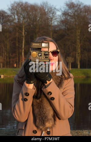 Jeune femme photographiant avec un appareil photo instantané Banque D'Images