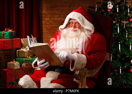 Le Père Noël est assis dans sa chaise face à présente et l'arbre de Noël Banque D'Images