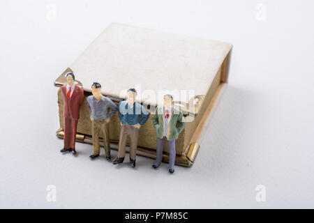 Petite figurine d'hommes modèles trouvés à côté d'un livre Banque D'Images