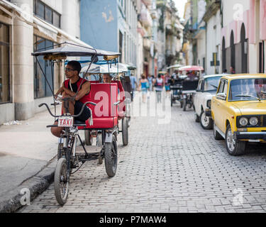 Location d'un chauffeur de taxi attend son prochain passager dans une rue animée de la Vieille Havane, Cuba. Banque D'Images