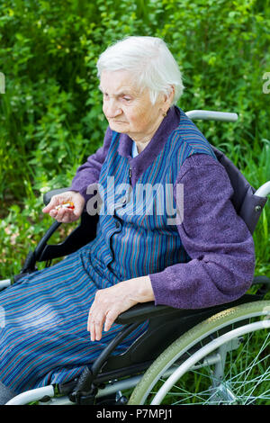 Vieille dame assise en fauteuil roulant souffrant de démence en plein air temps de dépenses Banque D'Images