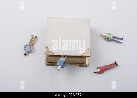 Petite figurine d'hommes modèles trouvés à côté d'un livre Banque D'Images
