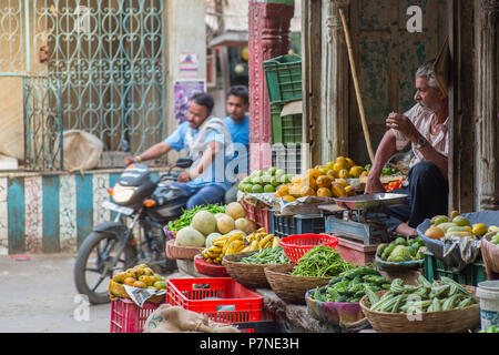 Vendeur de fruits et légumes locaux assis sur dans son magasin à Pushkar, Inde, sur une rue animée comme moto par les lecteurs. Banque D'Images