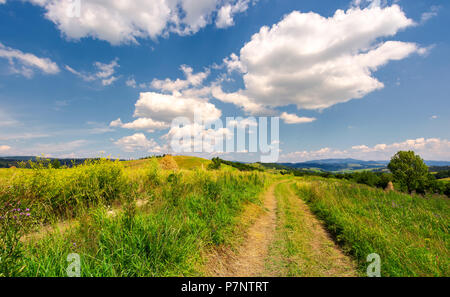 Beau paysage rural dans les montagnes. joli paysage d'été. route à travers champ agricole sous le ciel bleu avec des nuages Banque D'Images