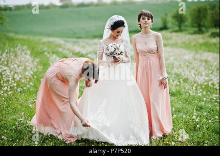 Belles demoiselles avec bride sur le terrain plein de fleurs le jour du mariage. Banque D'Images