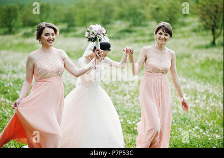 Belles demoiselles avec bride sur le terrain plein de fleurs le jour du mariage. Banque D'Images