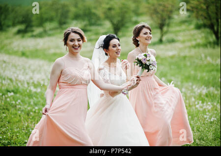 Belles demoiselles avec bride sur le terrain plein de fleurs le jour du mariage. Banque D'Images