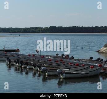 Scène au bord de l'eau - une ligne de bateaux de pêche amarrés sur l'eau sur une fin d'après-midi à Hanningfield réservoir, Essex, Angleterre. Banque D'Images