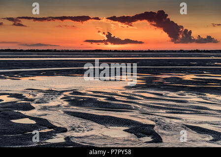 Lumière orange lever du soleil sur l'embouchure de la Somme. Le ciel se reflète dans les flaques de la marée basse Banque D'Images