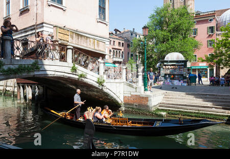 Les touristes à travers l'aviron Gondolier Cannaregio, Venise, Vénétie, Italie dans son sandolo Campo Santi Apostoli, en passant sous un pont Banque D'Images