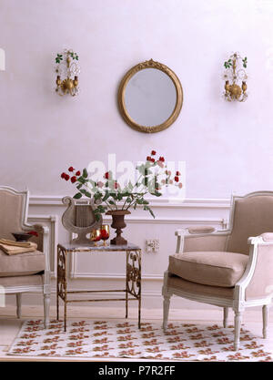 Style Français peint gris rembourrés chaises et table en métal petite économie dans un salon de style avec les feux de mur de chaque côté du miroir Banque D'Images