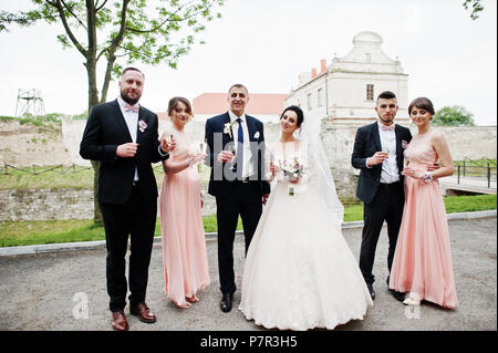 Couple de mariage et les garçons avec des demoiselles de boire du champagne dans le parc. Banque D'Images