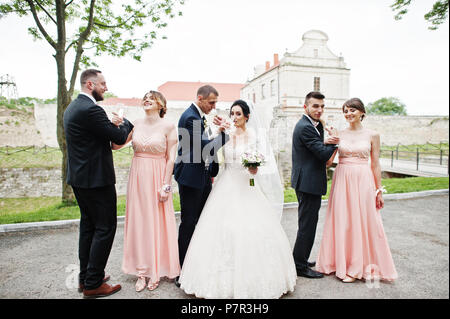 Couple de mariage et les garçons avec des demoiselles de boire du champagne dans le parc. Banque D'Images