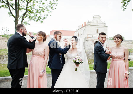 Couple de mariage et les garçons avec des demoiselles de boire du champagne dans le parc. Banque D'Images