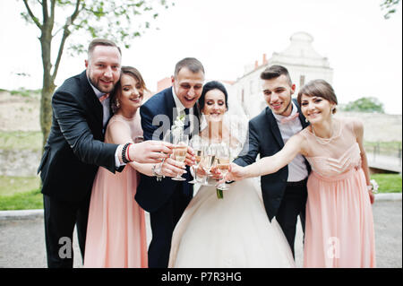 Couple de mariage et les garçons avec des demoiselles de boire du champagne dans le parc. Banque D'Images