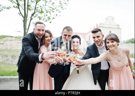 Couple de mariage et les garçons avec des demoiselles de boire du champagne dans le parc. Banque D'Images