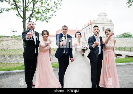 Couple de mariage et les garçons avec des demoiselles de boire du champagne dans le parc. Banque D'Images