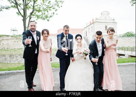 Couple de mariage et les garçons avec des demoiselles de boire du champagne dans le parc. Banque D'Images