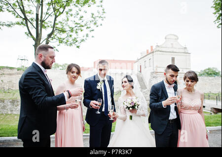 Couple de mariage et les garçons avec des demoiselles de boire du champagne dans le parc. Banque D'Images