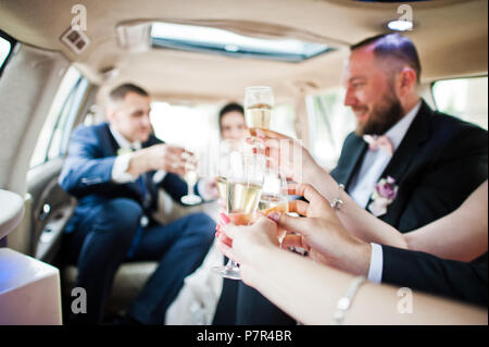 Garçons et filles avec wedding couple drinking champagne dans la voiture. Banque D'Images