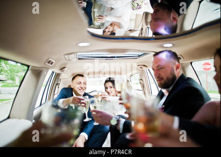 Garçons et filles avec wedding couple drinking champagne dans la voiture. Banque D'Images