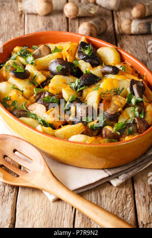 Champignons des bois délicieux avec des pommes de terre et cheddar fromage dans un plat allant au four, sur la table. vertical, style rustique Banque D'Images