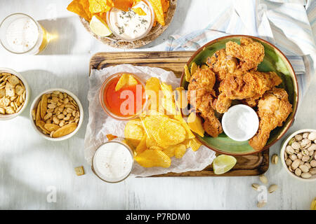 Poulet frit, de la bière et des collations et de la bière sur une surface en bois blanc, vue du dessus Banque D'Images