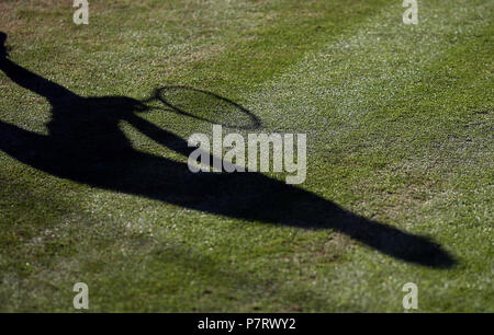 L'ombre d'un joueur de tennis sur le court sur la sixième journée des championnats de Wimbledon à l'All England Lawn Tennis et croquet Club, Wimbledon. Banque D'Images