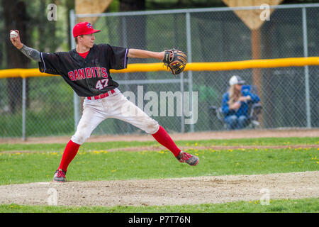 La prestation de Pitcher la hauteur, en pleine course, les garçons d'après-midi d'un match de baseball junior. Cranbrook, BC. Banque D'Images