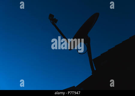 Silhouette Accueil antenne satellite antennes de télévision numérique sur le toit de maison sur fond de ciel bleu foncé Banque D'Images