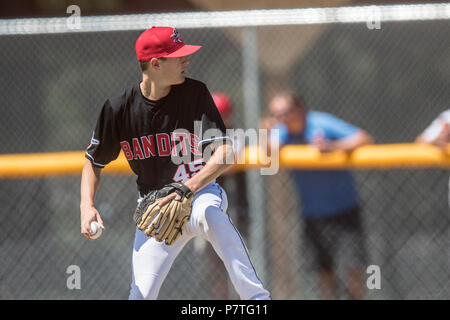 La prestation de Pitcher la hauteur, en pleine course, montrant l'adhérence, les garçons d'après-midi d'un match de baseball junior. Cranbrook, BC. Banque D'Images