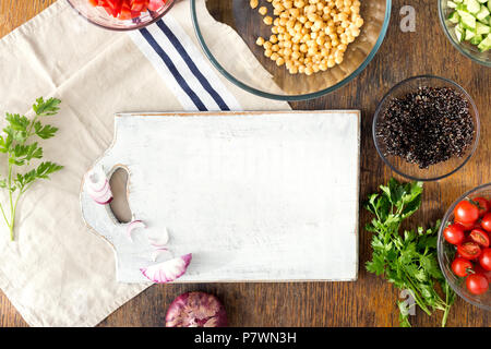 Autour de la cuisine en bois noir, le quinoa, les pois chiches, les poivrons, l'oignon, le concombre, les tomates et le persil sur table en bois rustique, vue du dessus. Ingrédients Banque D'Images