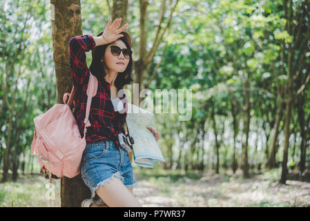 Asian female traveler fatiguant de perdu son chemin dans la forêt. Femme essuyant la sueur à la main. Fille soloe voyages et de l'aventure concept. Portrait et Li Banque D'Images