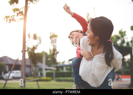 Maman câlin et transporter son fils. La préparation d'envoyer ses enfants à l'école le matin. Retour à l'école d'éducation et de concept. Famille heureuse et pleine d'amour de Banque D'Images