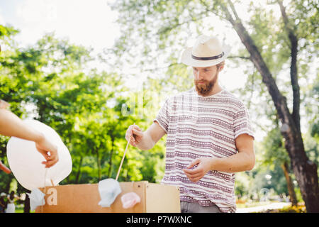 Thème photo sucreries de petite entreprise. Un jeune homme avec une barbe d'un négociant de race blanche dans le chapeau le propriétaire de la sortie fait la barbe à papa, fairy Banque D'Images