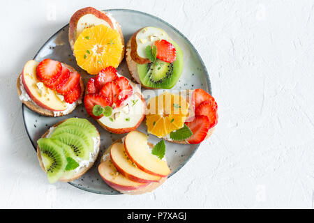 Dessert de fruits des sandwiches à base de ricotta. Délicieux petit déjeuner sain des toasts avec du fromage à la crème, fruits frais biologiques et de baies, herbes, noix et Banque D'Images