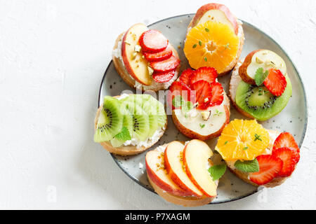 Dessert de fruits des sandwiches à base de ricotta. Délicieux petit déjeuner sain des toasts avec du fromage à la crème, fruits frais biologiques et de baies, herbes, noix et Banque D'Images