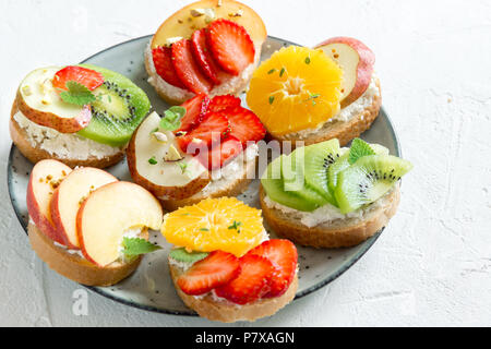 Dessert de fruits des sandwiches à base de ricotta. Délicieux petit déjeuner sain des toasts avec du fromage à la crème, fruits frais biologiques et de baies, herbes, noix et Banque D'Images