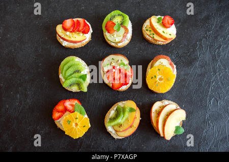 Dessert de fruits des sandwiches à base de ricotta. Délicieux petit déjeuner sain des toasts avec du fromage à la crème, fruits frais biologiques et de baies, herbes, noix et Banque D'Images