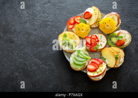 Dessert de fruits des sandwiches à base de ricotta. Délicieux petit déjeuner sain des toasts avec du fromage à la crème, fruits frais biologiques et de baies, herbes, noix et Banque D'Images