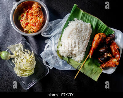 Repas thaï typique de riz blanc (khaw ou koe su-ay, gai tod (poulet grillé), le chou cru et épicé salade de papaye (som tam) Banque D'Images