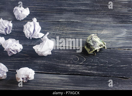 Un dollar froissé sur une table à côté des boules de papier blanc. Le processus de réflexion et de trouver de nouvelles idées d'affaires, des solutions rentables. De l'attraction en Banque D'Images